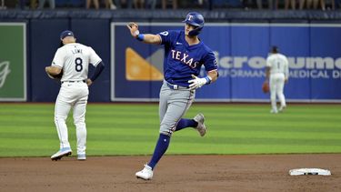 Josh Jung de los Rangers de Texas saluda al bullpen de su equipo al recorrer las bases tras conectar un jonrón de tres carreras frente a los Rays de Tampa Bay el lunes 1 de abril del 2024. (AP Foto/Steve Nesius)