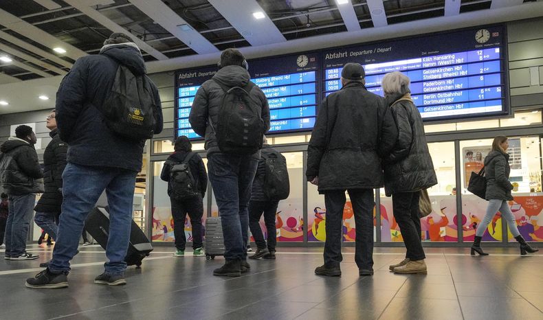 ARCHIVO - Un grupo de personas observa una pantalla informativa en la principal estación de trenes de Essen, Alemania, cuando la mayoría de los trenes fueron cancelados el jueves 16 de noviembre de 2023. (AP Foto/Martin Meissner)