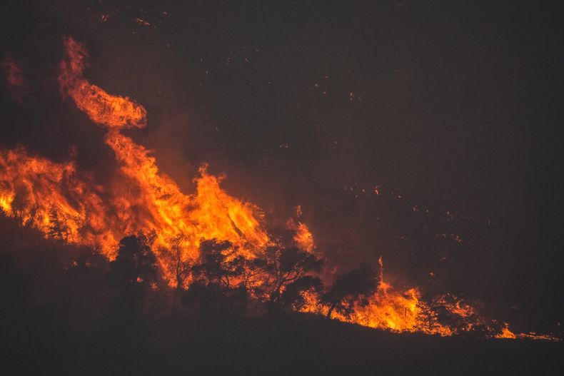 Un incendio consume una fila de árboles en una montaña cerca de Agioi Theodori, al oeste de Atenas, el lunes 17 de julio de 2023. (AP Foto/Petros Giannakouris)