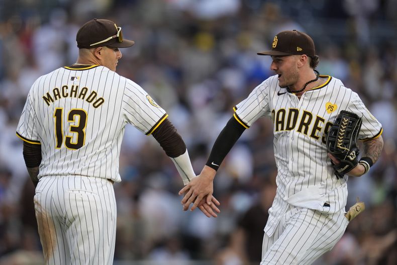 El bateador designado de los Padres de San Diego, Manny Machado (13), celebra con el jardinero central Jackson Merrill después de que los Padres derrotaron 4-0 a los Bravos de Atlanta el sábado 13 de julio de 2024, en San Diego. (AP Foto/Gregory Bull)