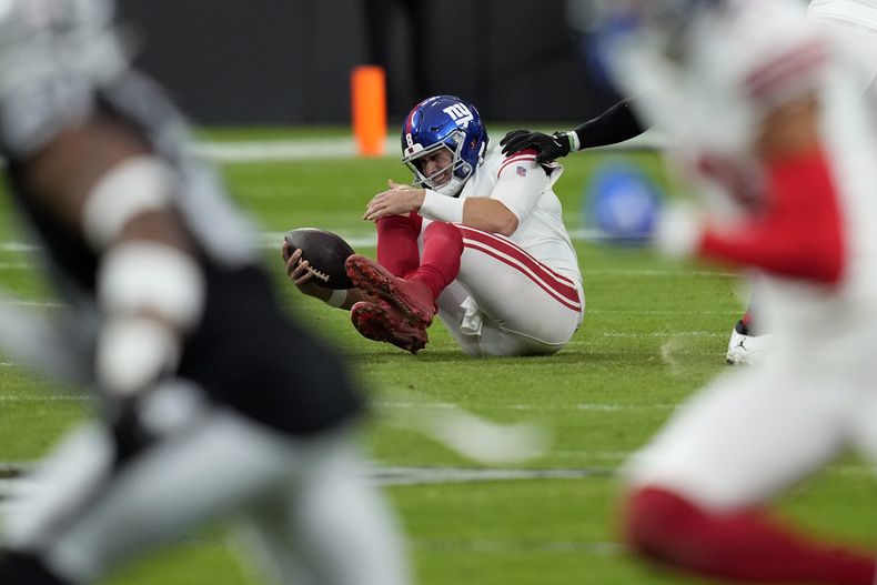 ARCHIVO - Daniel Jones, quarterback de los Giants de Nueva York, se sujeta la rodilla después de una captura durante la primera mitad del juego de la NFL en contra de los Raiders de Las Vegas, el domingo 5 de noviembre de 2023, en Las Vegas. Hablando después de que el equipo inició sus actividades organizadas, Jones dijo que no ha tenido retrocesos en su recuperación, el lunes 15 de abril de 2024. (AP Foto/John Locher, Archivo)