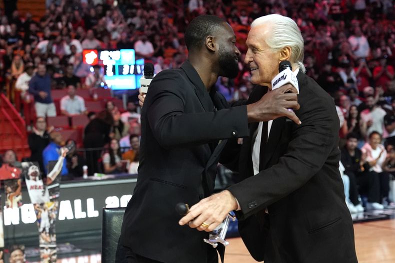 El ex jugador del Heat de Miami Dwayne Wade (izquierda) y el presidente del Heat Pat Riley (derecha) comparten durante la ceremonia de honor a la carrera de Wade y su inducción al Salón de la Fama del Baloncesto de Naismith Memorial el año pasado, durante el medio tiempo del juego de baloncesto entre los Hornets de Charlotte y el Heat de Miami, el domingo 14 de enero de 2024, en Miami. (AP Foto/Lynne Sladky)