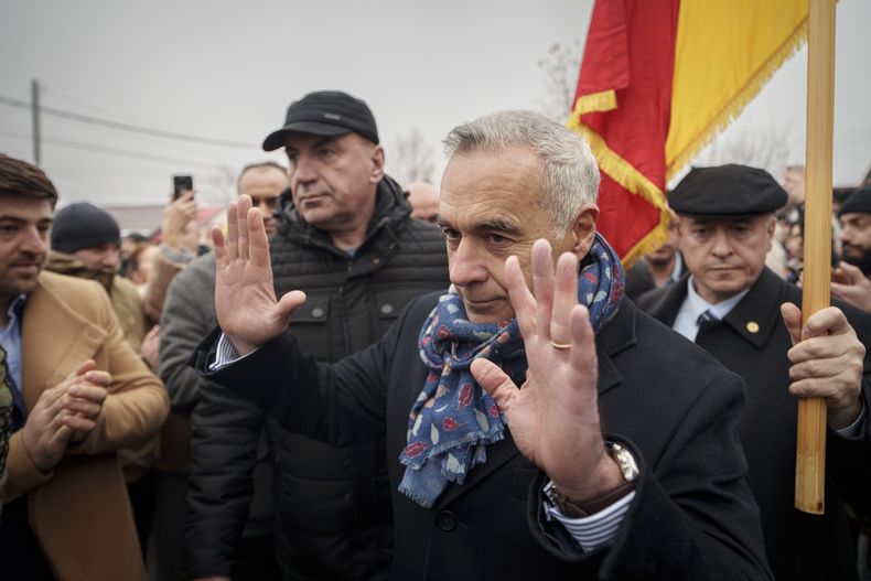 Calin Georgescu, Al frente, candidato independiente a presidente y que ganó la primera ronda de elecciones presidenciales, hace un gesto ante un centro de votación cerrado después de que la Corte Constitucional anulara el resultado de la primera ronda de los comicios, en Mogosoaia, Rumanía, el domingo 8 de diciembre de 2024. (AP Foto/Vadim Ghirda)