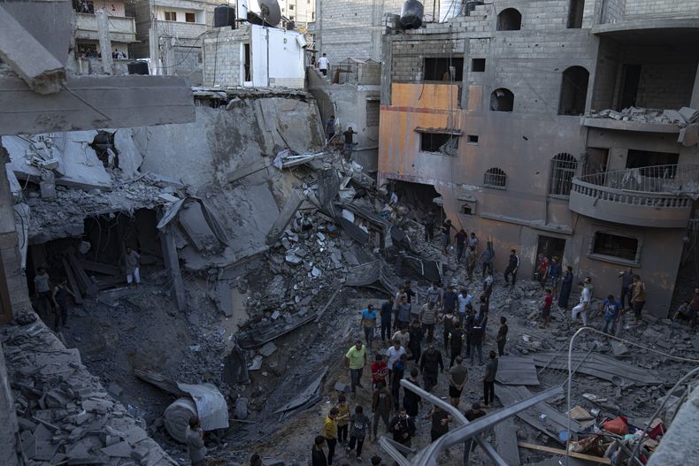 Palestinos buscan sobrevivientes entre los restos de un edificio destrozado por un bombardeo israelí, en Khan Younis, en la Franja de Gaza, el 19 de octubre de 2023. (AP Foto/Fatima Shbair)