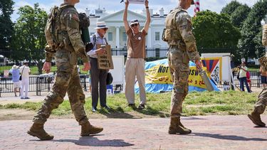 Miembros de la Guardia Nacional patrullan Lafayette Park cerca de la Casa Blanca, el viernes 29 de agosto de 2025, en Washington, mientras que el manifestante Will Roosien, de Grand Rapids, Michigan, que pretende inspirar a otras personas de su generación para que protesten, sostiene un cartel sobre el movimiento MAGA. (AP Foto/Jacquelyn Martin)