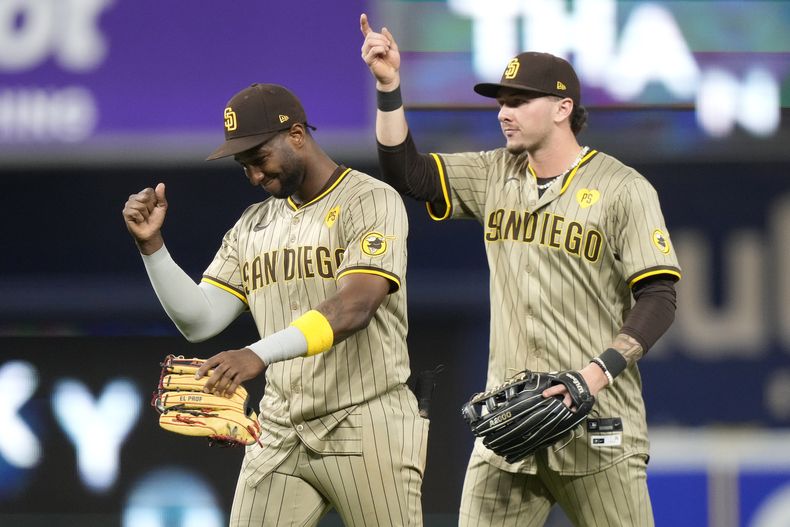 El jardinero izquierdo de los Padres de San Diego, Jurickson Profar, a la izquierda, y el jardinero central Jackson Merrill, a la derecha, celebran después de vencer a los Marlins de Miami, el sábado 10 de agosto de 2024, en Miami. (AP Foto/Lynne Sladky)
