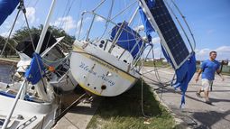 Drew Griffith camina junto a tres barcos que fueron arrastrados contra un dique tras el paso del huracán Helene en la cuenca de Seaplane de las Islas Davis, cerca del aeropuerto Peter O., el viernes 27 de septiembre de 2024 en Tampa, Florida. (Chris Urso/Tampa Bay Times vía AP)
