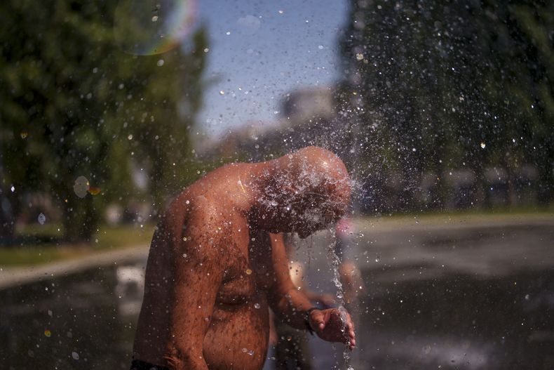 Un hombre se refresca en una playa urbana en el parque Madrid Río, el lunes 26 de junio de 2023, en Madrid. (AP Foto/Manu Fernandez)