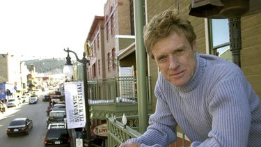 ARCHIVO - Robert Redford posa en un balcón en Main Street decorado con sus pancartas del Festival de Cine de Sundance el 17 de enero de 2003, en Park City, Utah. (Foto AP/Douglas C. Pizac, archivo)