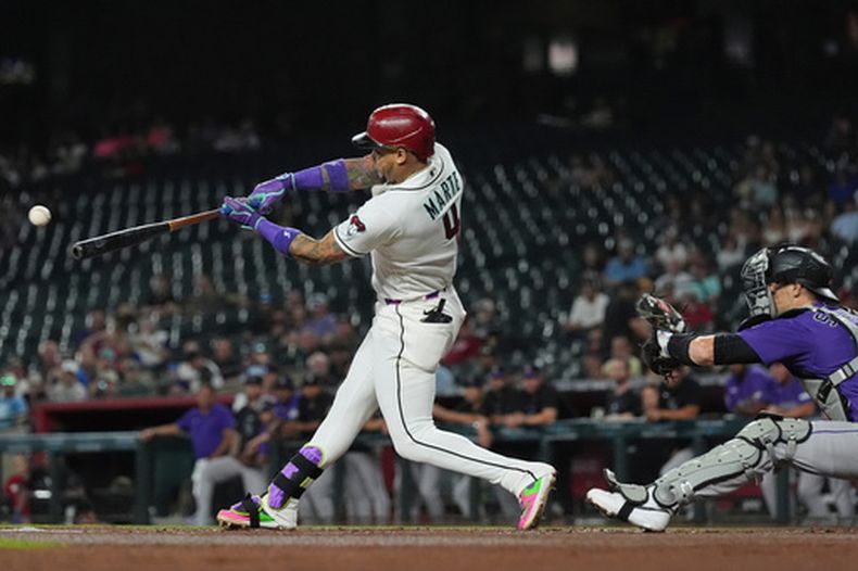 Ketel Marte (4), de los Dfiamondbacks de Arizona, batea un sencillo productor de una carrera mientras Brett Sullivan, receptor de los Rockies de Colorad, espera la pelota durante la primera entrada del juego de béisbol de Grandes Ligas, el miércoles 12 de agosto de 2026, en Phoenix. (AP Foto/Ross D. Franklin)