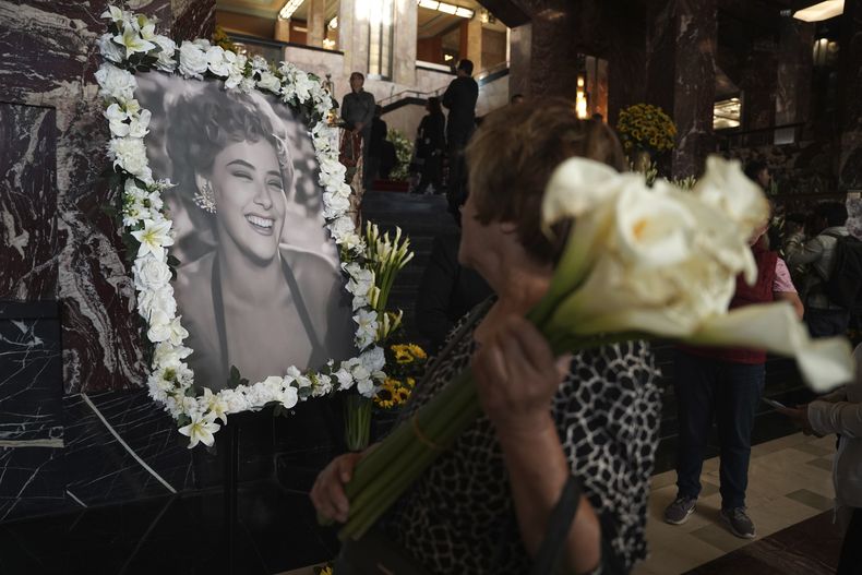 Un asistente mira un retrato enmarcado con flores de la actriz mexicana Silvia Pinal, durante su funeral en el Palacio de Bellas Artes, en la Ciudad de México, el sábado 30 de noviembre de 2024. Pinal, actriz de la Época de Oro del cine mexicano de lás décadas 1940 y 50, murió el jueves. Tenía 93 años. (Foto AP/Aurea Del Rosario)