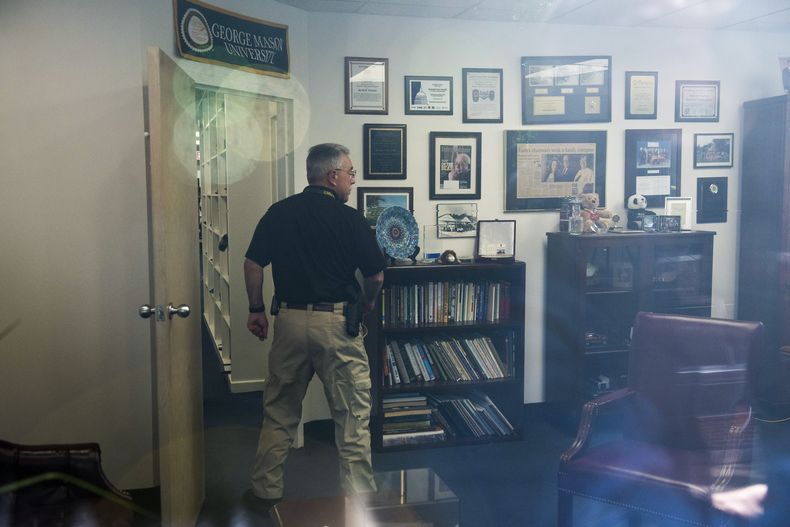 En esta imagen tomada a través de la ventana de una oficina, un agente de la policía revisa la oficina del representante Gerry Connelly, en Fairfax, Virginia, el lunes 15 de mayo de 2023, luego de que la policía informó que un hombre atacó a dos miembros del personal de la oficina el lunes por la mañana. (AP Foto/Cliff Owen)