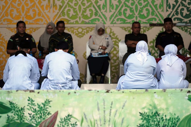 Varias personas condenadas por violar la ley islámica, incluyendo a una pareja de novios sancionados por besarse durante una retransmisión en vivo en TikTok, esperan su turno para ser azotados en público, en Banda Aceh, Indonesia, el 2 de julio de 2026. (AP Foto/Reza Saifullah)