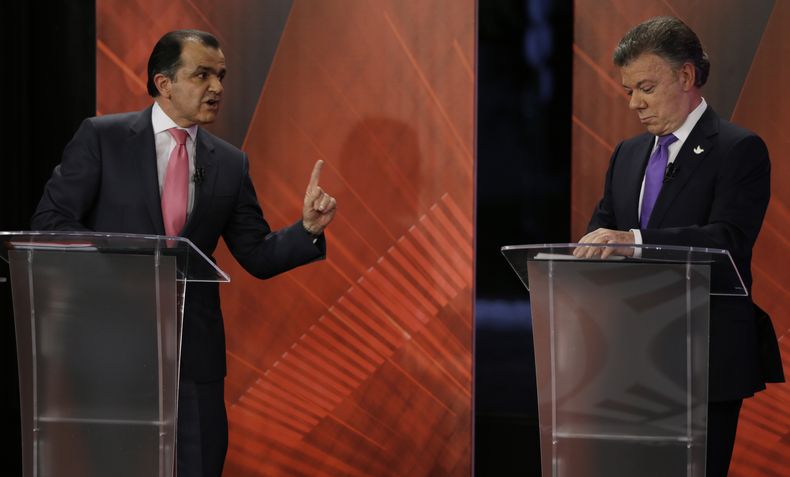 El presidente Juan Manuel Santos, derecha, que aspira a un segundo per&iacute;odo, escucha al candidato opositor Oscar Iv&aacute;n Zuluaga, durante un debate televisado en Bogot&aacute;, Colombia, 9 de junio de 2014. Los dos se enfrentan en la segunda ron