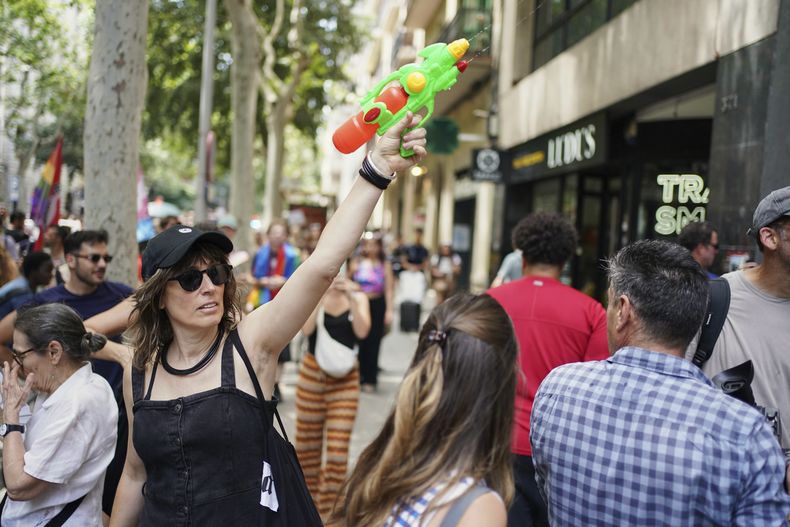 Una manifestante con una pistola de agua participa en una protesta contra el turismo excesivo, el domingo 15 de junio de 2025, en Barcelona. (AP Foto/Pau Venteo)