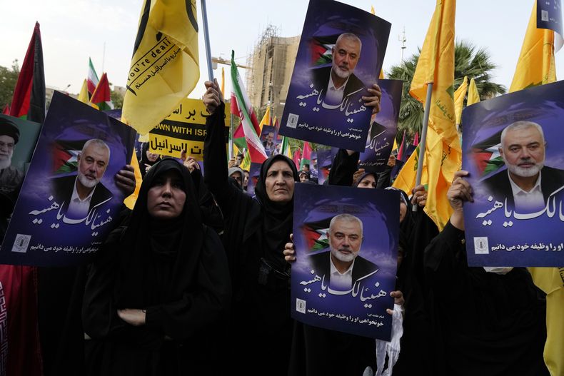 Manifestantes iraníes asisten a una protesta para condenar el asesinato del líder de Hamás Ismail Haniyeh mientras sostienen carteles con la frase (en árabe) ¡Felicidades Haniyeh!, en la Plaza Felestin (Palestina) de Teherán, Irán, el 31 de julio de 2024. (AP Foto/Vahid Salemi)