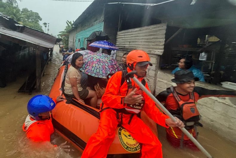 En esta imagen publicada por la Agencia Nacional de Búsqueda y Rescate de Indonesia (BASARNAS), rescatistas en un bote de goma evacúan a residentes de su hogar inundado en la provincia de Sumatra del Norte, Indonesia, el martes 25 de noviembre de 2025. (BASARNAS via AP)