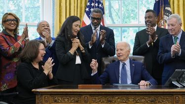 El presidente Joe Biden, junto a líderes de derechos civiles, miembros de la comunidad y funcionarios electos, habla tras entregar a la secretaria del Interior, Deb Haaland, cuarta de izquierda derecha, la pluma que uso para firmar la proclamación para designar como monumento nacional el sitio de los disturbios raciales de 1908 en Springfield, en la Oficina Oval de la Casa Blanca en Washington, el viernes 16 de agosto de 2024. (AP Foto/Susan Walsh)