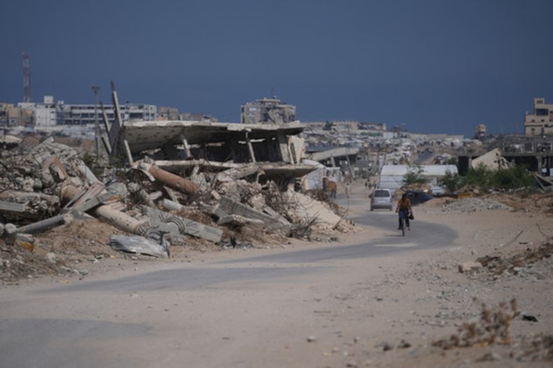 Un palestino pasa en bicicleta junto a escombros de edificios destruidos durante la guerra entre Israel y Hamás, en Jan Yunis, en el sur de Gaza, el 31 de julio de 2026. (AP Foto/Abdel Kareem Hana)