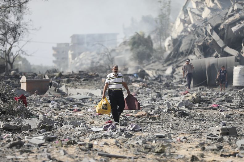 Palestinos caminan entre edificios destruidos por bombardeos israelíes sobre al-Zahra, a las afueras de la Ciudad de Gaza, el 20 de octubre de 2023. (AP Foto/Ali Mahmoud)