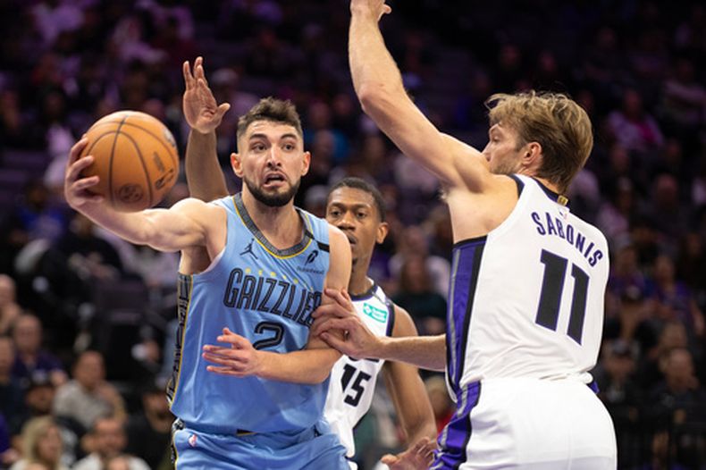 Ty Jerome (2), de los Grizzlies de Memphis, pasa el balón mientras Domantas Sabonis (11), de los Kings de Sacramento, defiende durante la primera mitad del juego de baloncesto de la NBA, el domingo 25 de octubre de 2026, en Sacramento, California. (AP Foto/Jose Luis Villegas)
