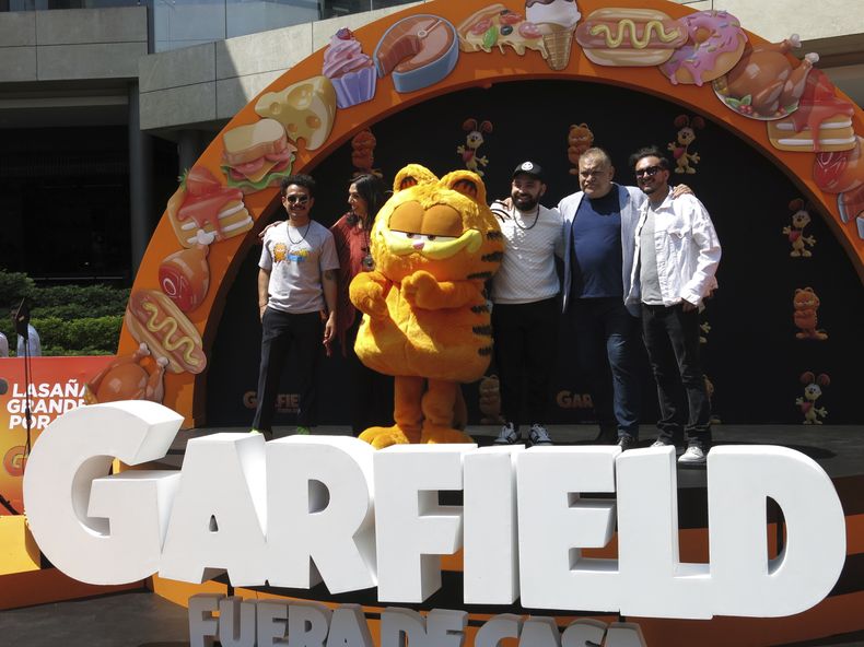 Un artista disfrazado como el personaje Garfield, centro, con los actores de doblaje Guillermo Memo Villegas, de izquierda a derecha, Regina Orozco, Jose Luis Slobotzky, Joaquín Cosio y Ricardo Pérez, posan en la alfombra naranja de la versión en español para Latinoamérica de The Garfield Movie en la Ciudad de México el domingo 28 de abril de 2024. (Foto AP/Berenice Bautista)