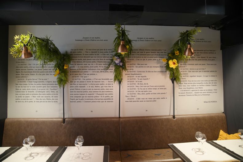 Flores colocadas permanentemente junto a un extracto de la obra de teatro de Milan Kundera Jacques et son Maitre en un restaurante cerca de su casa en París, el miércoles 12 de julio de 2023. Milan Kundera, cuyos escritos disidentes en la Checoslovaquia comunista lo transformaron en un exiliado satírico del totalitarismo, ha muerto en París. Tenía 94 años. (AP Photo/Christophe Ena)