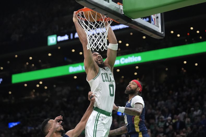 Jayson Tatum (0), de los Celtics de Boston, clava el balón para conseguir puntos frente a Brandon Ingram, derecha, de los Pelicans de Nueva Orleans, en la segunda mitad del juego de baloncesto de la NBA, el lunes 29 de enero de 2024, en Boston. (AP Foto/Steven Senne)