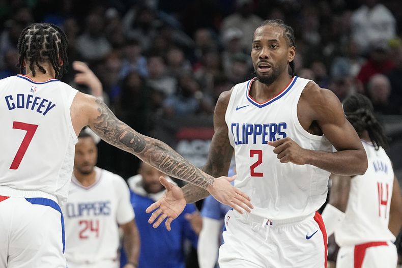 Kawhi Leonard, alero de los Clippers de Los Ángeles, recibe la felicitación de su compañero Amir Coffey, tras encestar ante los Mavericks de Dallas, el miércoles 20 de diciembre de 2023 (AP Foto/LM Otero)