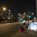 ARCHIVO - En esta imagen, iluminada por un flash externo, una mujer pasa por delante de una tienda de campaña de una persona sin hogar con una silla, en el centro de Los Ángeles, el 16 de febrero de 2023. (AP Foto/Jae C. Hong, archivo)