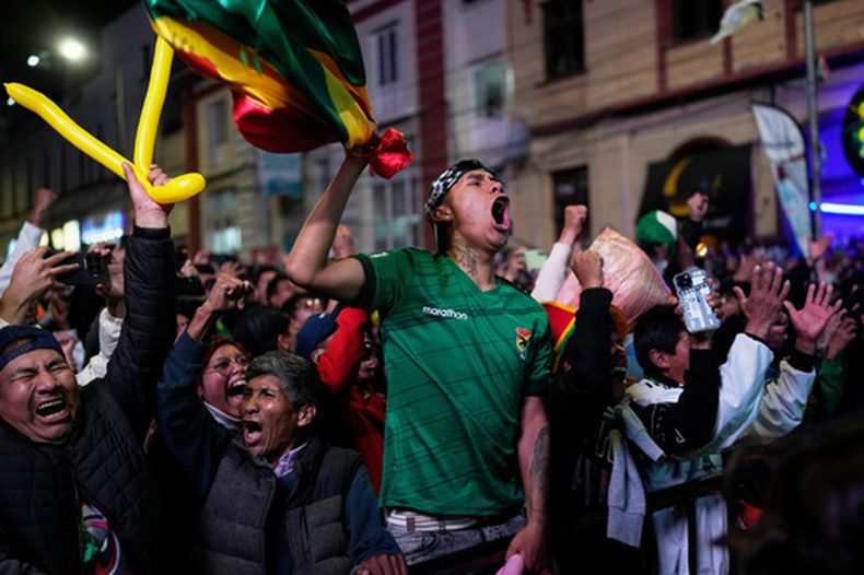 Hinchas bolivianos festejan la victoria de su país ante Surinam al mirar en pantalla gigante en La Paz el partido del repechaje mundialista disputado en México el jueves 26 de marzo de 2026 (AP Foto/Juan Karita)
