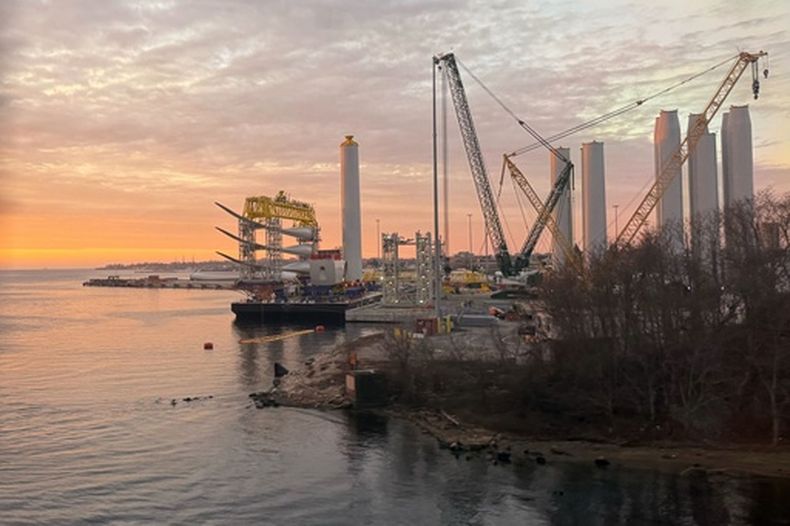 Hélices y bases de turbinas eólicas marinas se observan en una zona de estacionamiento en el muelle estatal de New London, Connecticut, el miércoles 14 de enero de 2026. (Foto AP/Matt OBrien)