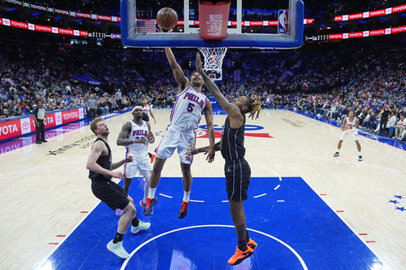 Quentin Grimes (5), de los 76ers de Filadelfia, se eleva para tirar ante Noah Clowney, de los Nets de Brooklyn, durante la primera mitad de un juego de baloncesto de la NBA, el sábado 14 de marzo de 2026, en Filadelfia. (Foto AP/Matt Rourke)