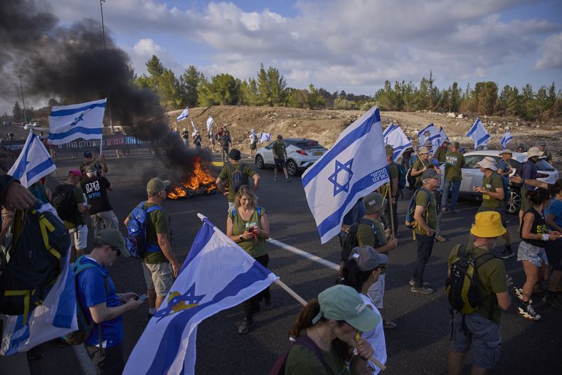 Manifestantes bloquean una carretera durante una protesta que exige la liberación inmediata de los rehenes retenidos por Hamás y pide al gobierno israelí que revoque su decisión de tomar Ciudad de Gaza y otras áreas en la Franja de Gaza, cerca de Jerusalén, Israel, el domingo 17 de agosto de 2025. (AP Foto/Ohad Zwigenberg)