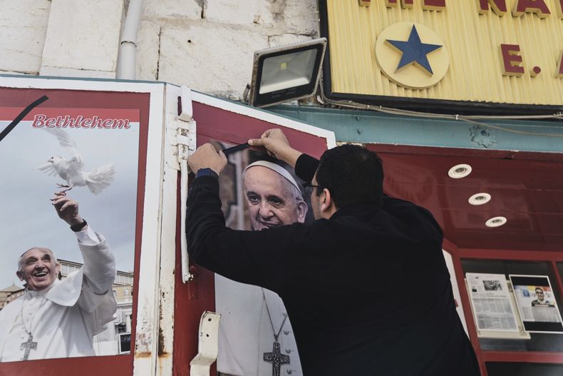 Un propietario de una tienda coloca un lazo negro sobre una foto del fallecido papa Francisco al conocer la noticia de su muerte a los 88 años, en Belén, Cisjordania, el lunes 21 de abril de 2025. (AP Foto/Mahmoud Illean)