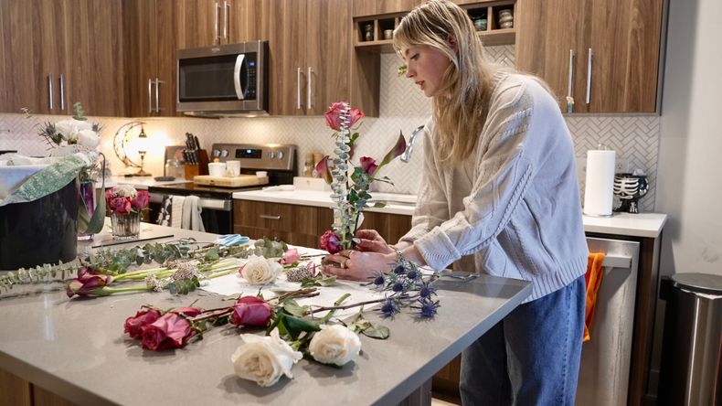 Megan Feller arregla ramos de flores para una fiesta de Halloween en su apartamento en Edina, Minnesota, el sábado 25 de octubre de 2025. (AP Foto/Mark Vancleave)