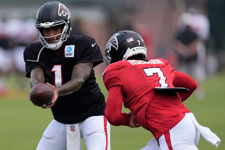 Tua Tagovailoa (1), quarterback de los Falcons de Atlanta, entrega el balón al corredor Bijan Robinson (7) durante un ejercicio en el campamento de entrenamiento del equipo, el viernes 7 de agosto de 2026, en Flowery Branch, Georgia. (AP Foto/Mike Stewart)
