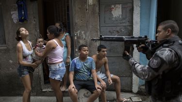 americateve | Un pol&iacute;cia militar, derecha, patrulla una calle en la favela Mare en R&iacute;o de Janeiro el martes, 25 de marzo de 2014. (AP Photo/Felipe Dana)