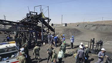 En esta foto publicada por la Sociedad de la Media Luna Roja Iraní, mineros y policías se ven junto a una mina de carbón donde una fuga de metano provocó una explosión el sábado en Tabas, unos 540 kilómetros (335 millas) al sureste de la capital, Teherán, Irán, el domingo 22 de septiembre de 2024. (Sociedad de la Media Luna Roja Iraní, via AP)