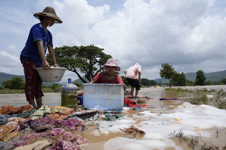Residentes lavan la ropa en una calle anegada en Naipyidó, Myanmar, el 15 de septiembre de 2024. (AP Foto/Aung Shine Oo)