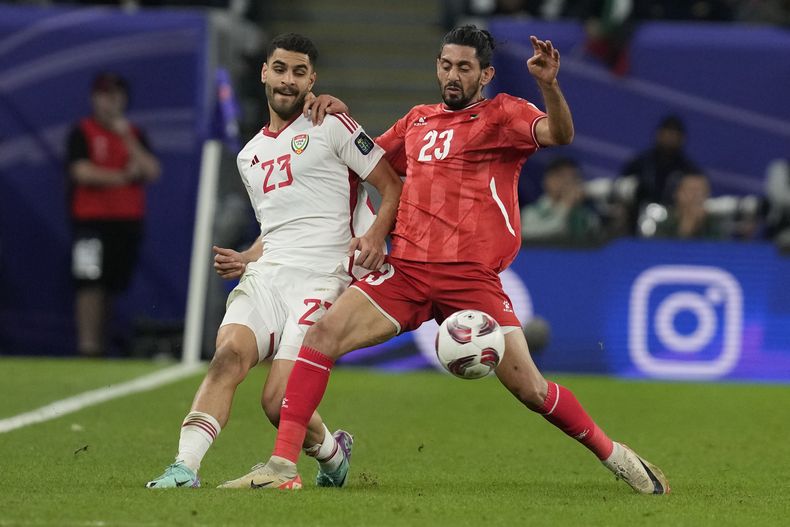 Sultan Adil Alameeri de los Emiratos Árabes Unidos y ,Attaa Jaber de Palestina pelean por el balón en el encuentro del Grupo C de la Copa Asiática en Al Wakrah, Qatar el jueves 18 de enero del 2024. (AP Foto/Thanassis Stavrakis)
