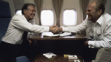 ARCHIVO - El expresidente Jimmy Carter estrecha la mano del expresidente Gerald Ford abordo del avión presidencial el 10 de octubre de 1981, entre El Cairo y España. (AP Foto/Dirck Halstead, archivo)