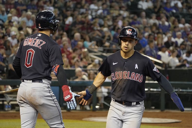 Steven Kwan, derecha, de los Guardianes de Cleveland, es felicitado por Andrés Gímenez en el plato después de anotar en contra de los Diamondbacks de Arizona, durante la cuarta entrada del juego de béisbol, el domingo 18 de junio de 2023, en Phoenix. (AP Foto/Darryl Webb)