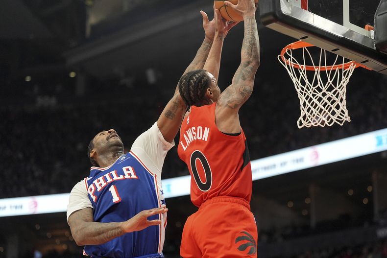 A.J. Lawson (0), de los Raptors de Toronto, recibe un tapón al intentar una clavada frente a Andre Drummond (1), de los 76ers de Filadelfia, durante la primera mitad del juego de baloncesto de la NBA, el miércoles 12 de marzo de 2025, en Toronto. (Frank Gunn/The Canadian Press vía AP)