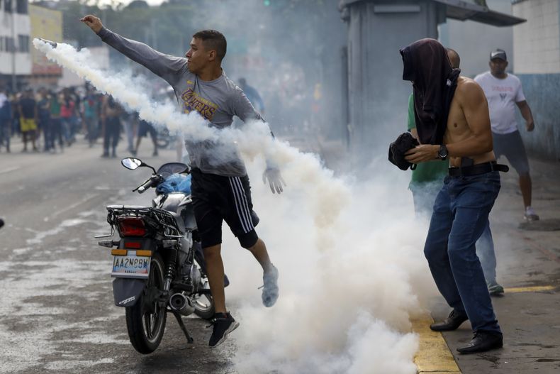 Un manifestante arroja una bombona de gas a la policía durante las manifestaciones contra los resultados oficiales de las elecciones presidenciales, un día después de que el presidente Nicolás Maduro fuera declarado vencedor de los comicios en Caracas, Venezuela, el lunes 29 de julio de 2024. (AP Foto/Cristian Hernández)