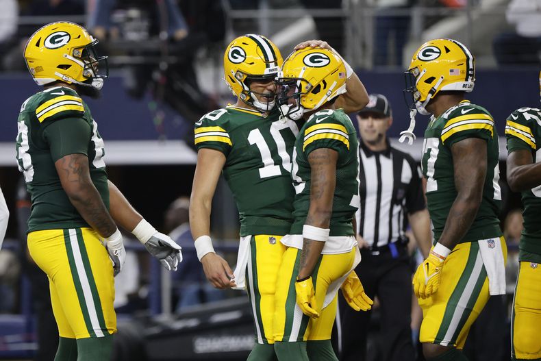 El quarterback de los Packers de Green Bay Jordan Love (10) celebra junto al wide receiver Dontayvion Wicks (13) luego de combinarse para un pase de touchdown durante la primera mitad del juego de la NFL ante los Cowboys de Dallas, el domingo 14 de enero de 2024, en Arlington, Texas. (AP Foto/Michael Ainsworth)
