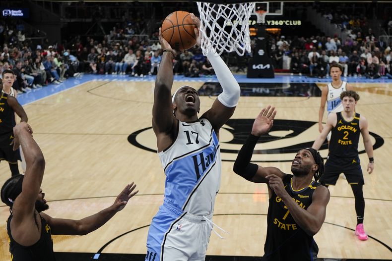 El alero de los Hawks de Atlanta, Onyeka Okongwu (17), dispara contra el escolta de los Warriors de Golden State, Buddy Hield (7), durante la primera mitad de un partido de baloncesto de la NBA, el sábado 22 de marzo de 2025, en Atlanta. (AP Foto/Mike Stewart)