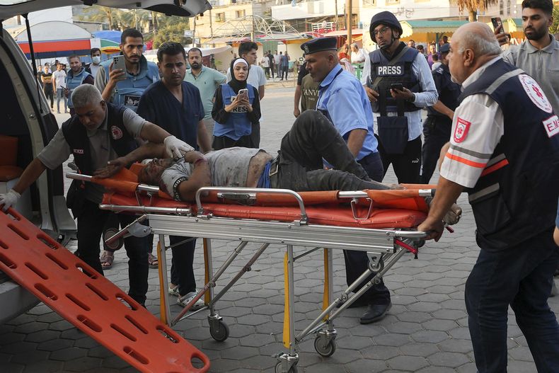 En esta imagen de archivo, reporteros observan mientras un palestino herido en un bombardeo israelí es llevado a un hospital en Deir el-Balah, en la Franja de Gaza, el 16 de octubre de 2023. El limitado número de periodistas que están en Gaza tratan de informar sobre la guerra con Israel mientras sufren los mismos problemas que la asediada población palestina de la Franja. (AP Foto/Adel Hana, archivo)