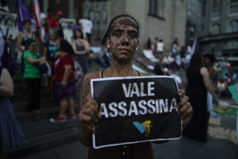 ARCHIVO - Una activista cubierta de barro posa con un cartel en el que se lee Vale asesina durante una manifestación en Sao Paulo, Brasil, 1 de febrero de 2019. (AP foto/Victor R. Caivano, archivo)