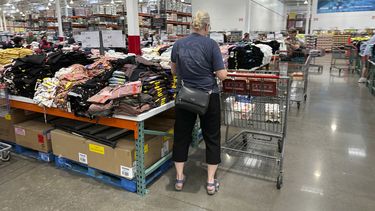 Una compradora junto a pilas de ropa en un almacén de la cadena Costco el jueves 22 de junio de 2023 en Colorado Springs, Colorado. (AP Foto/David Zalubowski)